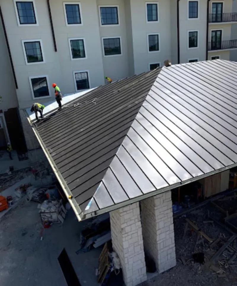 Crew installing standing seam metal roof panels on a commercial project in Islip